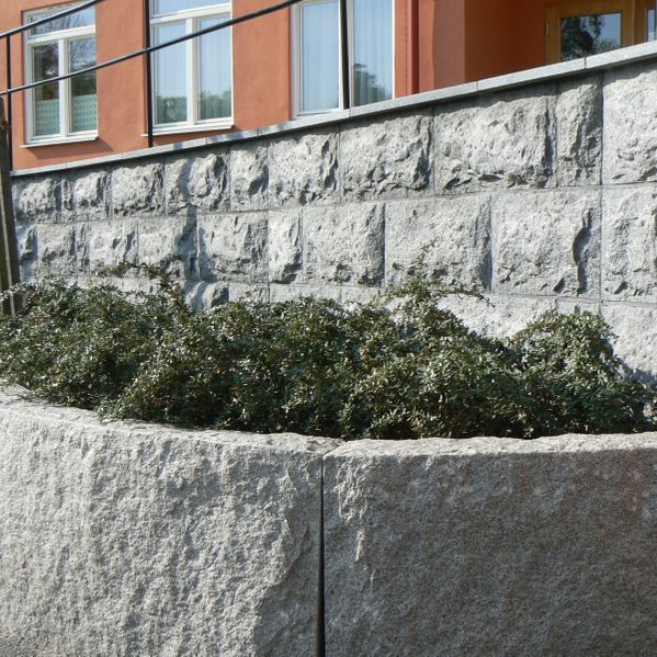 granitmur vid fastighet med buskar