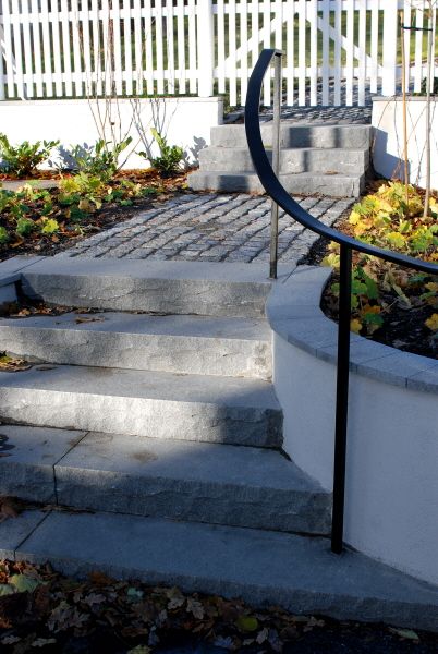 gråa stentrappor till villa entré med marksten, plantage och svart räcke